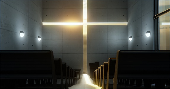 An upward perspective reveals a walkway between benches within a contemporary church, culminating at a concrete wall adorned with a carved cross.