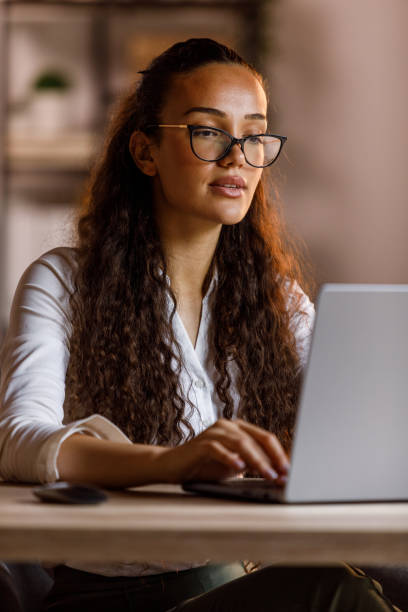 istock Young woman with eyeglasses working at her desk, using laptop 1703892566