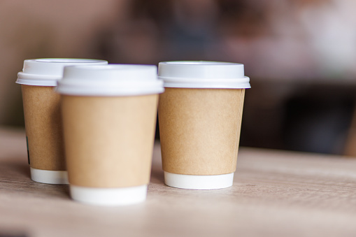 Close up shot of three cups of takeaway coffee on a desk for a coffee break at the office.