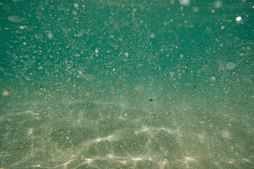 Under the clear blue sea at Pedn Vounder Beach, Cornwall. The seas movement disturbing the sea bed.