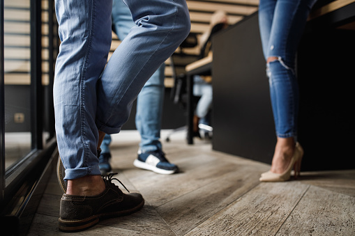 Low section of unrecognizable people standing in office space and chatting during work break.