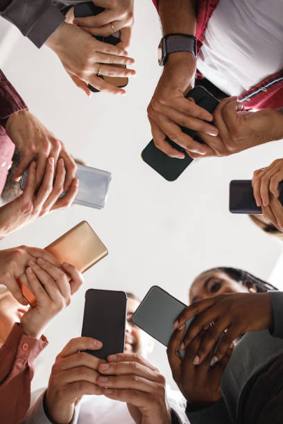 istock Group of people standing in a circle and using their smart phones 1703924903