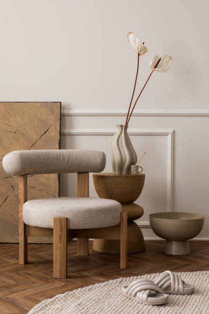 Cozy composition of living room interior with stylish gray armchair, wooden stand, vase with flowers, beige bowl, roung carpet, stylish slippers, wall with stucco and personal accessories. Home decor. Template. acogedora composición del interior de la sala de estar con elegante sillón gris, soporte de madera, jarrón con flores, cuenco beige, alfombra roung, zapatillas elegantes, pared con estuco y accesorios personales. decoración del hogar. plantilla.