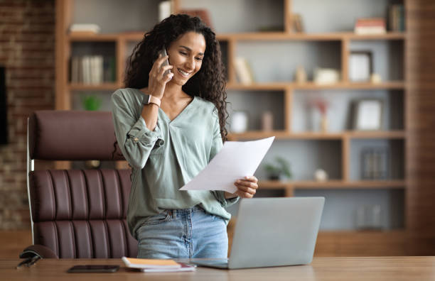istock Happy brunette woman having phone conversation, reading documents 1703935336