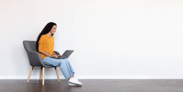 istock Cheerful brunette woman freelancer using laptop at home, white background 1703935343