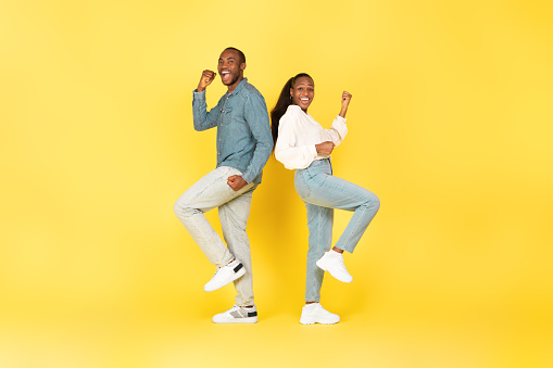 Joyful African American Couple Gesturing Yes Celebrating Great Success Posing Standing On Yellow Studio Background. Joy And Victory Celebration Concept. Full Length Shot