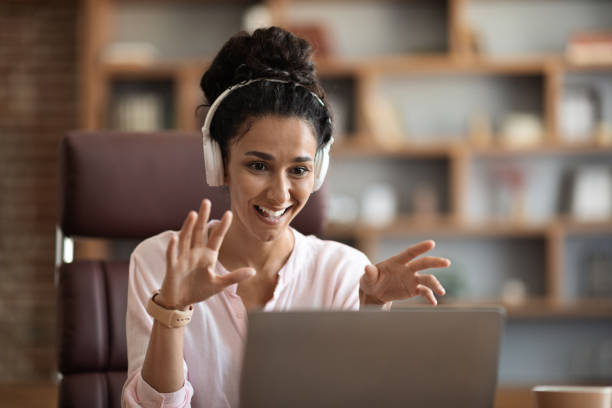 istock Stylish pretty lady having video chat, using laptop and headphones 1703937177