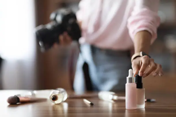 Photo of Unrecognizable woman beauty blogger taking photo of cosmetics, using camera