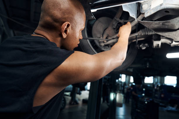 istock African American mechanic working under the car using long screwdriver 1703942742
