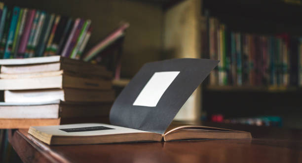 Vintage style.An open book or textbook vintage style in the library with light from the window on the reading table and the corridor of the bookshelves in a Stack of books background.Education learning concept