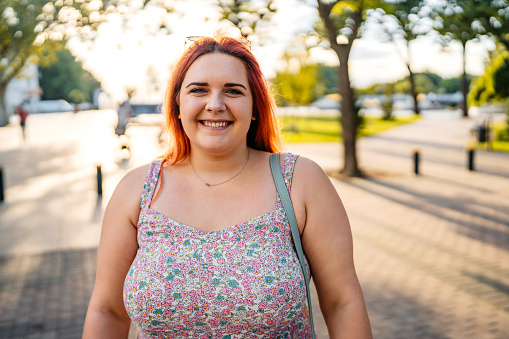 Portrait of a beautiful young plus size woman standing in the park.