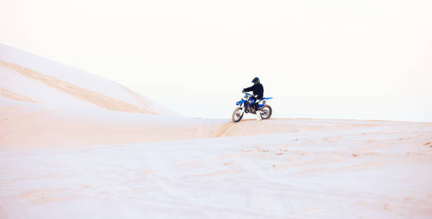 desert, hill or athlete driving motorcycle for action, adventure or fitness with performance or adrenaline. sand, sports or person on dirt motorbike on dunes for training, exercise or race challenge - driving training car safety imagens e fotografias de stock