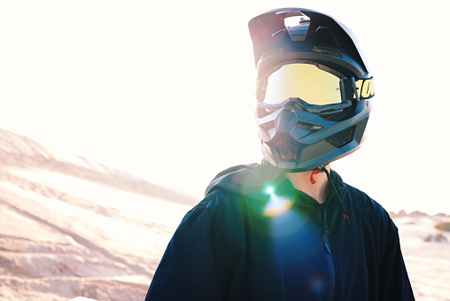 Helmet, flare and an off road biker outdoor for a race, competition or adrenaline in summer. Freedom, energy and adventure with a sports rider on a course for power or speed in a reflective visor