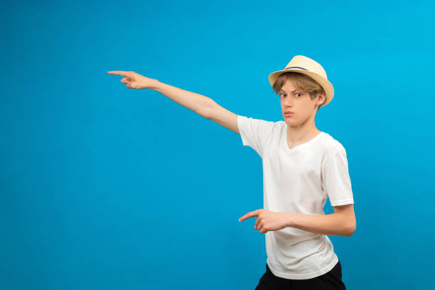istock Young teen man points palms aside isolated on blue. Friendly well-looking boy paying your attention at copy space, best deal, sale 1704010667