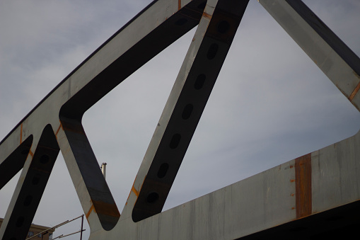 Bridge truss. Triangle of the supporting structure of the bridge. Steel truss sturdy construction. Details of transport architecture.