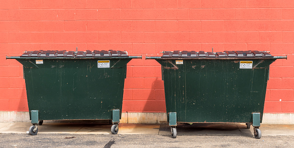Youngsville, Pennsylvania, USA September 25, 2023 Two metal dumpsters in front of a brick wall on a sunny fall day