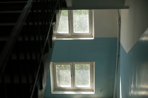 Interior with windows. Staircase inside the building. Two old windows with white frames. Inside the entrance of a residential building.