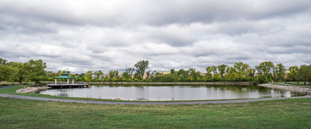istock Park Pond Panorama with Cloudscape in Early Fall 1704099185