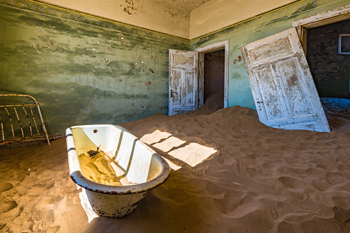 Old Diamond Mining Ghost Town Building Interior Panorama. Nature is coming back. Desert Sand entering old the abandoned german colonial house ín an old deserted Diamond Mine Ghost Town at Kolmanskop, Luderitz, Namibia, Africa.