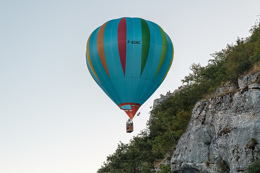Rocamadour, France - 24th September 2023: A hot air balloon appears to pass dangerously close to a cliff edge and spectators during the Montgolfiades de Rocamadour balloon festival in France