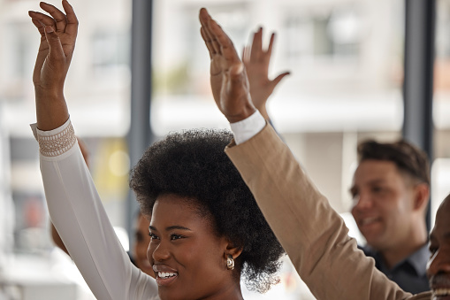 Happy business people, black woman or hands up in seminar for participation or learning skills. Vote, smile or audience asking questions in group mentorship, training or coaching in workshop together