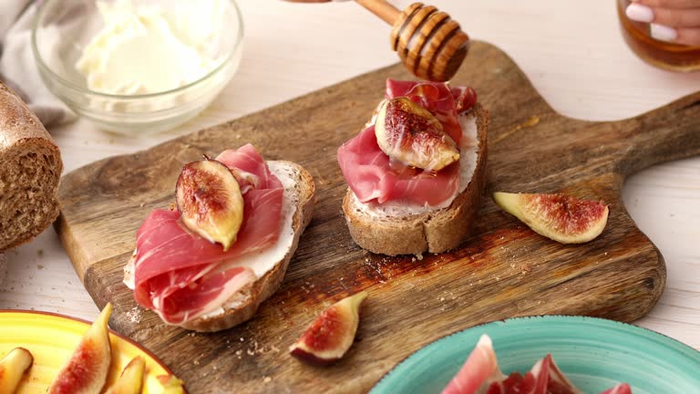 The process of making a sandwich with prosciutto and figs.