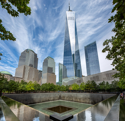 Ground Zero, Lower Manhattan, New York, USA - September 16, 2023.  A vertorama landscape of the reflecting pool memorial at Ground Zero and The One World Trade centre building in New York city
