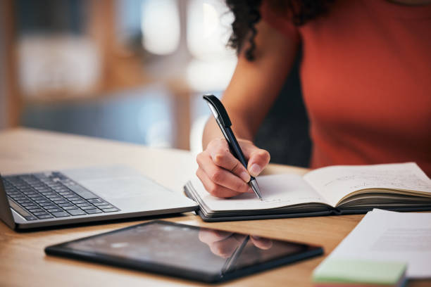 istock Notebook, pen and hands of person writing notes, schedule or event planner working on project agenda. Laptop, tablet and closeup worker planning checklist, journal or research plan, list or ideas 1704176246