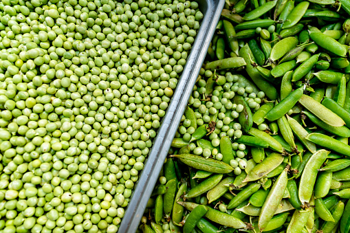 Close-up on fresh green peas in the produce aisle at the supermarket - food concepts