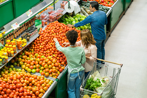 Latin American people shopping in the produce aisle at the supermarket - grocery shopping concepts
