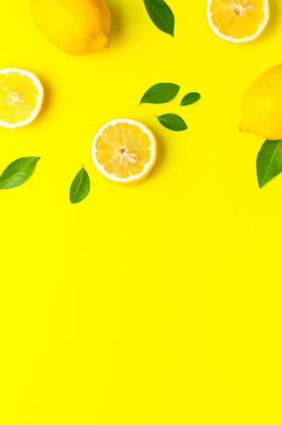 istock Creative background with fresh lemons and green leaves on bright yellow background. Top view flat lay copy space. Lemon fruit citrus minimal concept vitamin C. Composition with whole, slices of lemons 1704194976