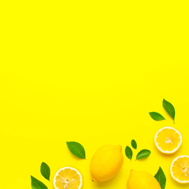 istock Creative background with fresh lemons and green leaves on bright yellow background. Top view flat lay copy space. Lemon fruit citrus minimal concept vitamin C. Composition with whole, slices of lemons 1704194977