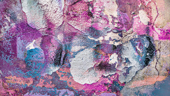 High Resolution old weathered bluish concrete wall detail, coated with multiple layers of white, orange, purple, magenta, emerald and other nuances of green paint, applied through the years randomly one on top of the other, cracking and peeling off, run down by the elements, grunge background texture stock photo.