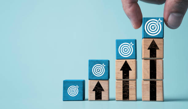 Hand stacking dartboard on the top of up arrow for enhance setup business objective target and goal concept.