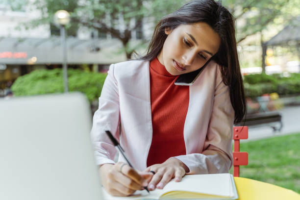 istock Young pensive Indian businesswoman, freelancer using laptop, taking notes 1704211013