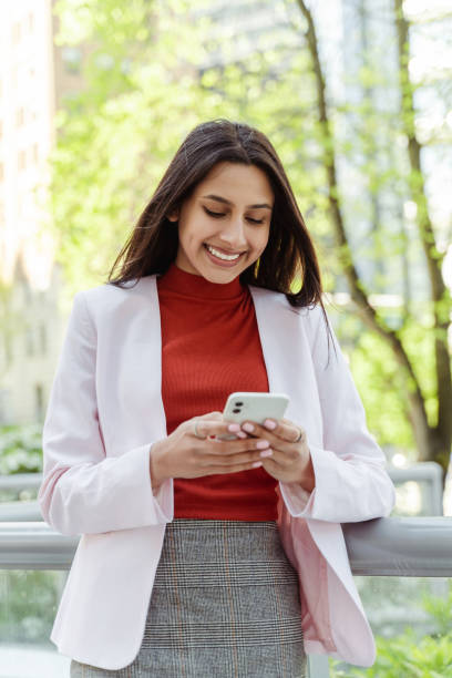 istock Beautiful smiling Indian woman holding mobile phone reading text message 1704211034