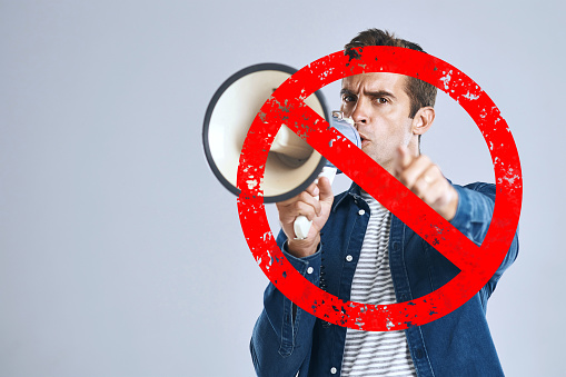 Megaphone, stop or angry man shouting in studio on white background for freedom or change. Overlay, news announcement or frustrated person screaming on loudspeaker for human rights speech or justice