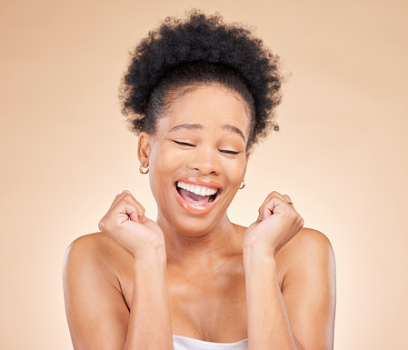Skincare, excited and young black woman in a studio with cosmetic, glow and natural face routine. Happy, smile and African female model with facial dermatology treatment isolated by brown background.
