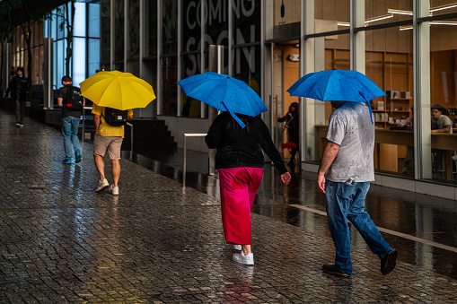 New York, USA - September 12, 2023: Pedestrians using umbrellas to shelter from the rain as they walk on the street in New York City, NY, USA