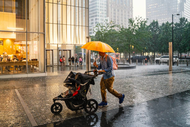 New York, USA - September 12, 2023: A man is walking with a baby stroller in the rain, New York City, USA