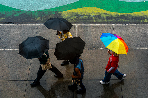 New York, USA - September 24, 2023: Pedestrians using umbrellas to shelter from the rain as they walk on the street in New York City, NY, USA