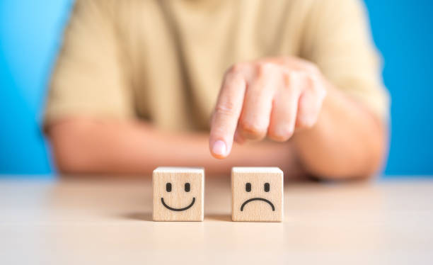 istock Hand making a decision between two wooden cubes with happy and sad face for positive or negative mindset selection. Emotional state and mental health concept. Like or Dislike for client satisfaction. 1704252659