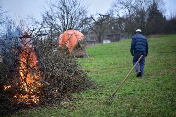 A gardener burns waste branches in a garden in a village traditionally stock photo
