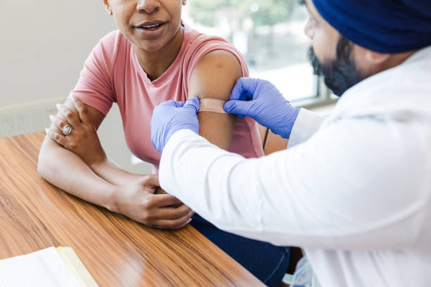 istock Male general practitioner carefully places a band aid on his patient 1704270685