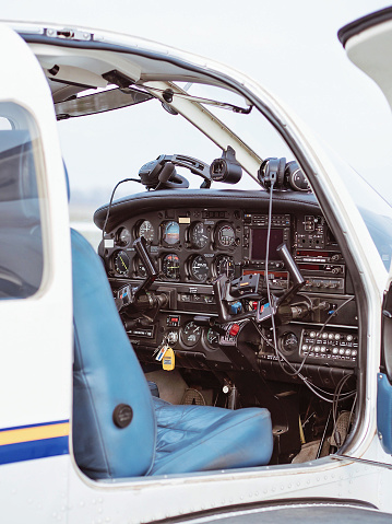 Cockpit view of a white private single-engine plane with flight instruments and a blue pilot seat from outside.