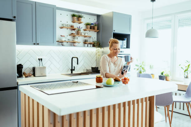 istock Mature woman enjoying time at home in kitchen with smart phone, using mobile app 1704292575