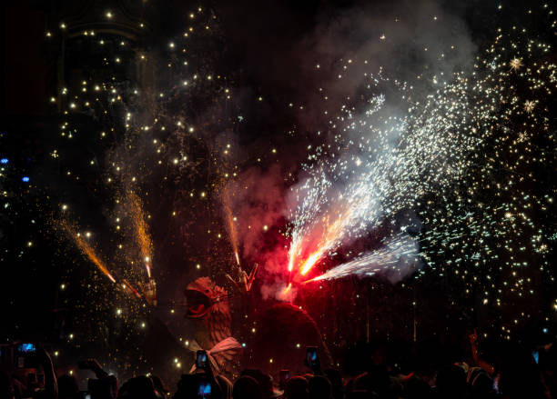 mitico drago che danza in uno spettacolo pirotecnico con fuochi d'artificio sparati dalla sua testa durante la tradizionale festa. le persone registrano con i loro telefoni cellulari. - spanish culture flash foto e immagini stock