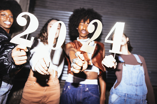 Group of friends holding the number 2024, celebration conceptual image for New Year’s Eve.
