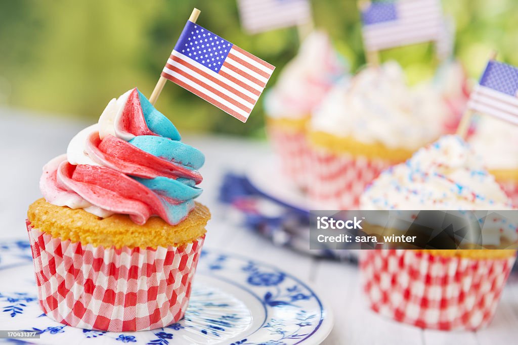 Cupcakes con rosso, bianco e blu glassa e bandiere americane sul tavolo all'aperto - Foto stock royalty-free di Bianco