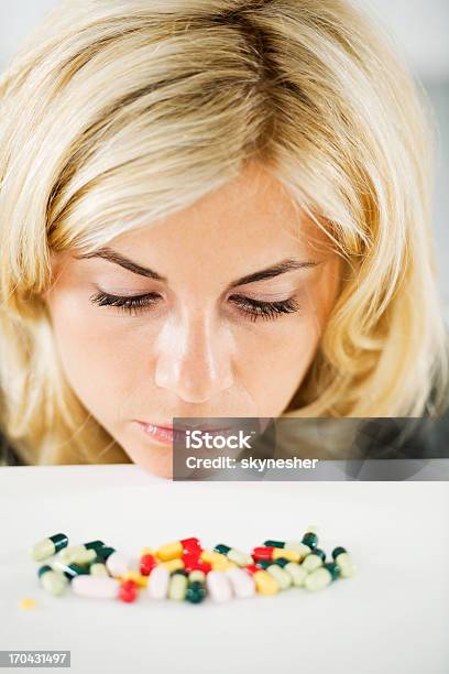 Beautiful Blonde Woman Is Looking At The Pile Of Pills Stock Photo - Download Image Now